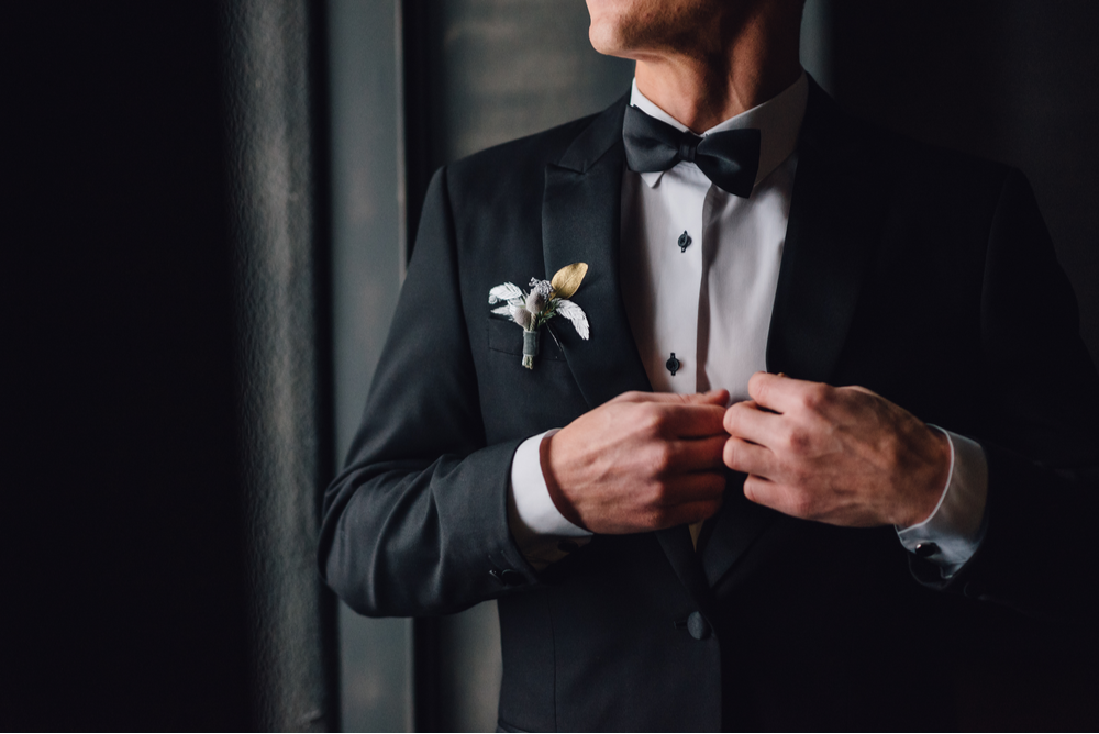 A groom in a black tuxedo getting ready for his wedding day